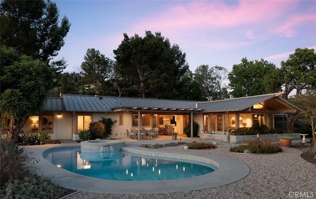 10551 Hillsboro Rd, North Tustin, CA 92705 - back of property with a standing seam roof, a metal roof, a patio, a pool with connected hot tub, and stucco siding