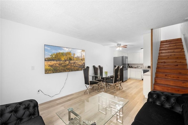 11025 Kittridge St Unit 128, North Hollywood, CA 91606 - living room with stairway, light wood-style flooring, ceiling fan, and a textured ceiling