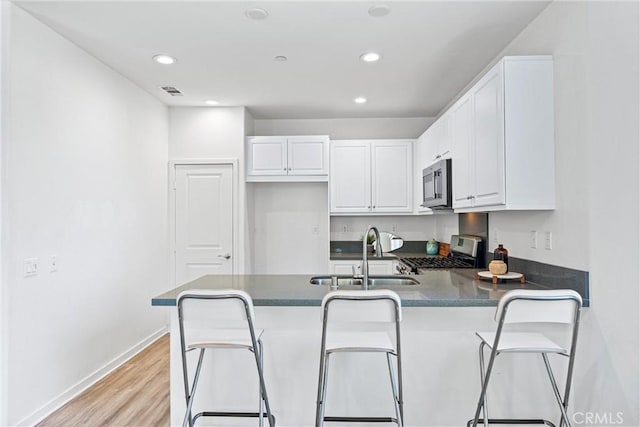 1166 Newberry Ln Unit 1, Claremont, CA 91711 - kitchen featuring stainless steel appliances, a peninsula, white cabinets, light wood-style floors, and recessed lighting
