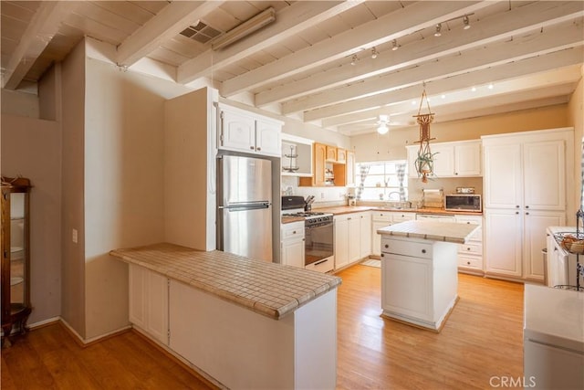 5772 Arrowhead Lake Rd, Hesperia, CA 92345 - kitchen with stainless steel appliances, light wood-style floors, white cabinetry, and beamed ceiling