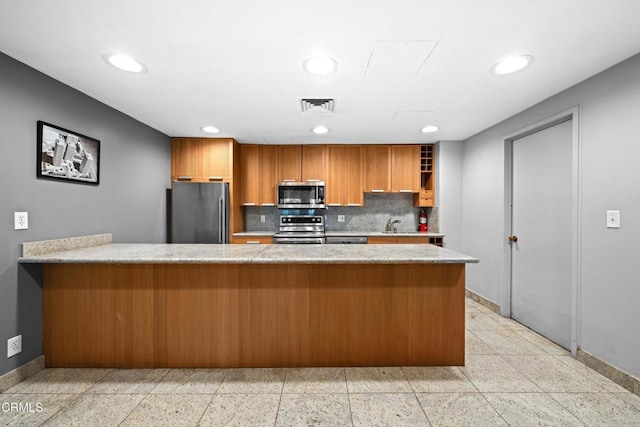 800 W 1st St Unit 1701, Los Angeles, CA 90012 - kitchen featuring appliances with stainless steel finishes, brown cabinetry, backsplash, recessed lighting, and a peninsula