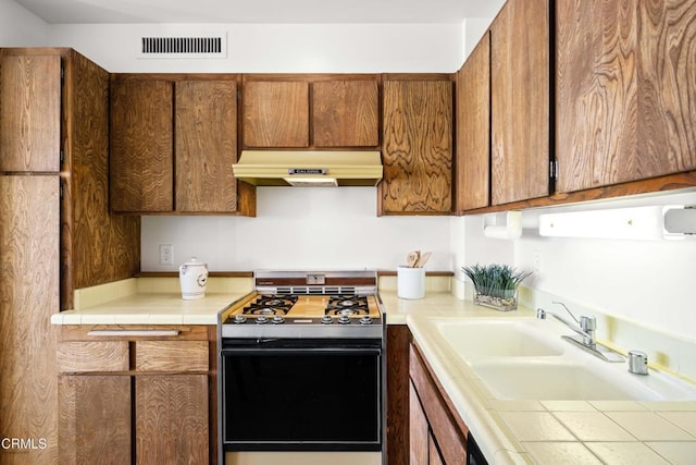 800 W 1st St Unit 1701, Los Angeles, CA 90012 - kitchen featuring gas range, range hood, brown cabinets, and tile counters