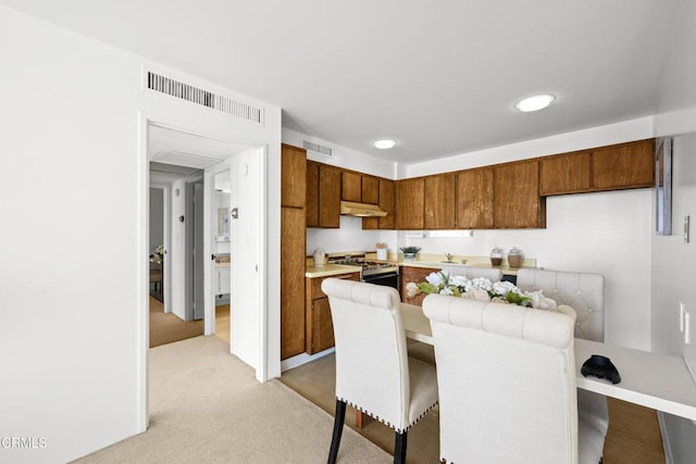 800 W 1st St Unit 1701, Los Angeles, CA 90012 - kitchen featuring light countertops, light colored carpet, brown cabinetry, gas range, and under cabinet range hood