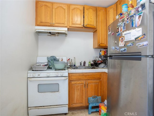 13114 S Main St, Los Angeles, CA 90061 - kitchen featuring freestanding refrigerator, gas range gas stove, under cabinet range hood, and brown cabinetry