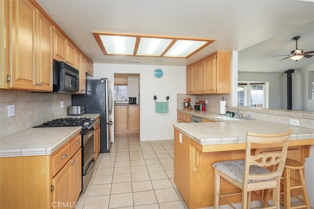 45337 Valley Oak Dr, Ahwahnee, CA 93601 - kitchen featuring range with gas stovetop, black microwave, decorative backsplash, a peninsula, and a breakfast bar