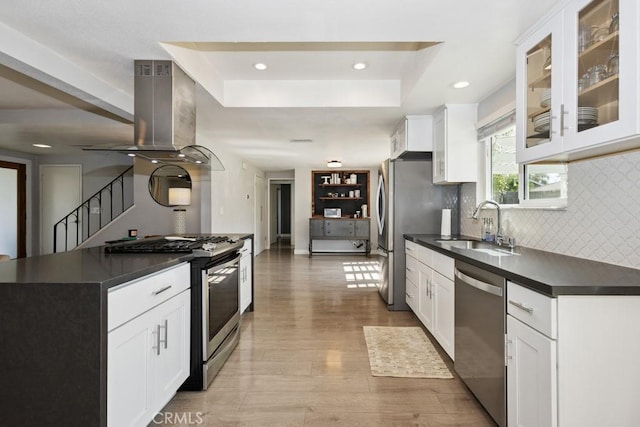 3314 Benton Ave, La Verne, CA 91750 - kitchen with appliances with stainless steel finishes, island range hood, dark countertops, a tray ceiling, and light wood-type flooring