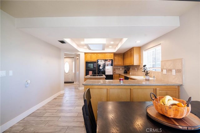26511 Mainsail Ln, Helendale, CA 92342 - kitchen featuring black appliances, a tray ceiling, a peninsula, light countertops, and wood finish floors