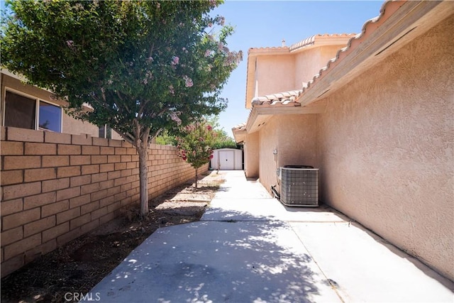 26511 Mainsail Ln, Helendale, CA 92342 - view of home's exterior featuring stucco siding, a storage shed, a patio, a tile roof, and a fenced backyard