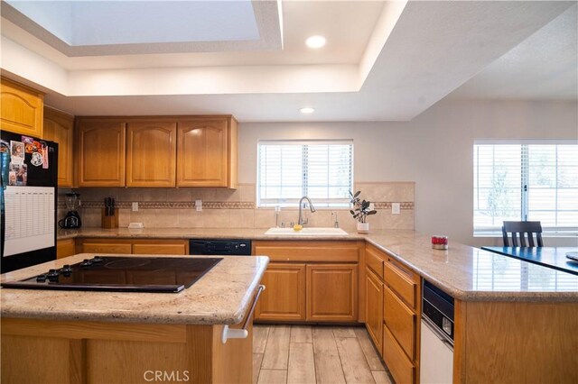 26511 Mainsail Ln, Helendale, CA 92342 - kitchen with black appliances, a peninsula, a tray ceiling, light stone counters, and tasteful backsplash