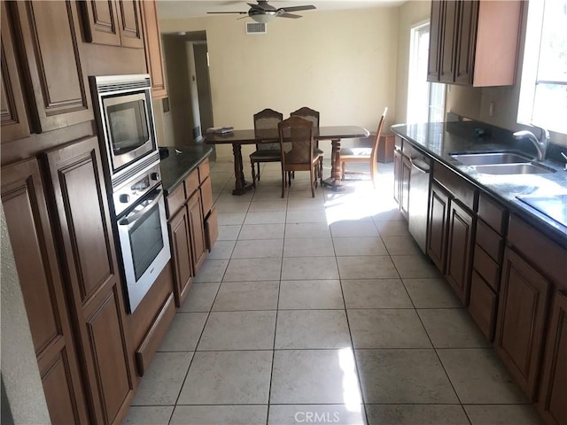 2710 Castle Rock Rd, Diamond Bar, CA 91765 - kitchen featuring appliances with stainless steel finishes, dark countertops, light tile patterned floors, and a ceiling fan