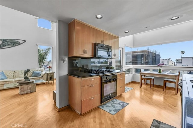 16745 Bayview Dr Unit B, Sunset Beach, CA 90742 - kitchen featuring black appliances, light wood-style flooring, recessed lighting, dark countertops, and brown cabinetry