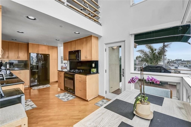 16745 Bayview Dr Unit B, Sunset Beach, CA 90742 - kitchen featuring black appliances, light wood-type flooring, decorative backsplash, dark countertops, and recessed lighting