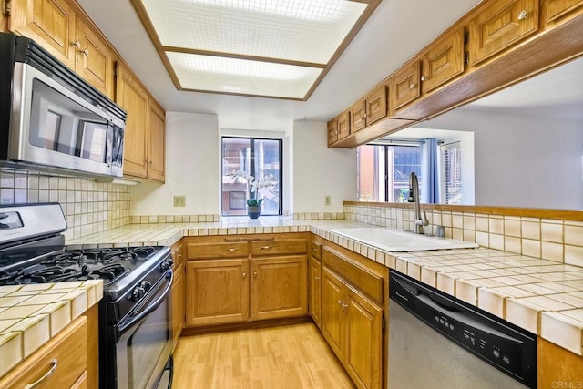4015 Canario St Unit E, Carlsbad, CA 92008 - kitchen with appliances with stainless steel finishes, tile countertops, decorative backsplash, light wood finished floors, and brown cabinetry