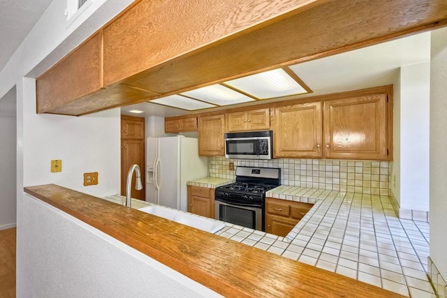 4015 Canario St Unit E, Carlsbad, CA 92008 - kitchen with appliances with stainless steel finishes, tile counters, decorative backsplash, and brown cabinetry