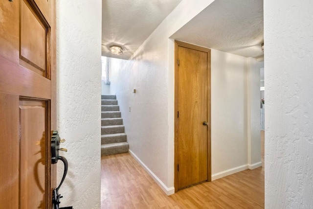 4015 Canario St Unit E, Carlsbad, CA 92008 - hall with light wood-style floors, a textured wall, stairway, and a textured ceiling