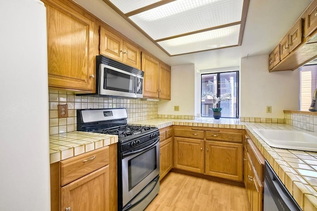 4015 Canario St Unit E, Carlsbad, CA 92008 - kitchen with stainless steel appliances, tile counters, light wood-style flooring, and decorative backsplash
