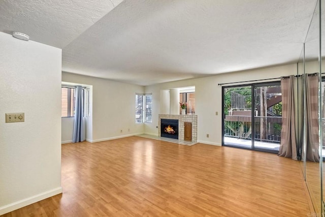 4015 Canario St Unit E, Carlsbad, CA 92008 - unfurnished living room with light wood-style floors, a textured ceiling, healthy amount of natural light, and a fireplace