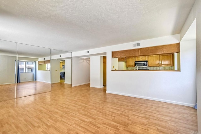 4015 Canario St Unit E, Carlsbad, CA 92008 - unfurnished living room with light wood-style floors and a textured ceiling