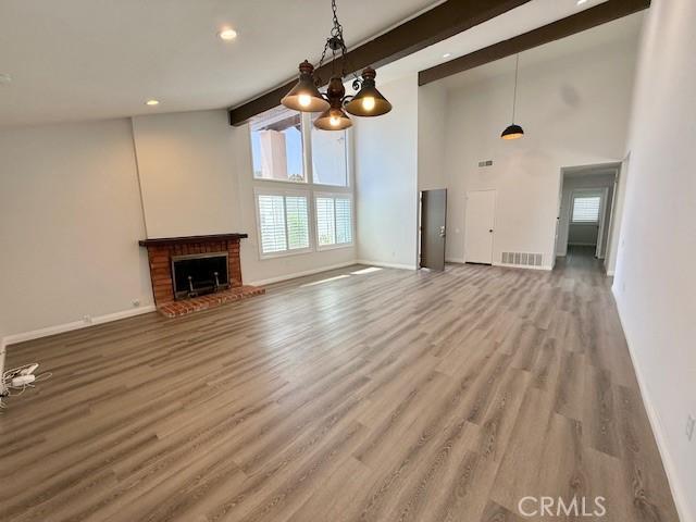 16413 Abascal Dr, Hacienda Heights, CA 91745 - unfurnished living room featuring wood finished floors, beam ceiling, a fireplace, high vaulted ceiling, and recessed lighting