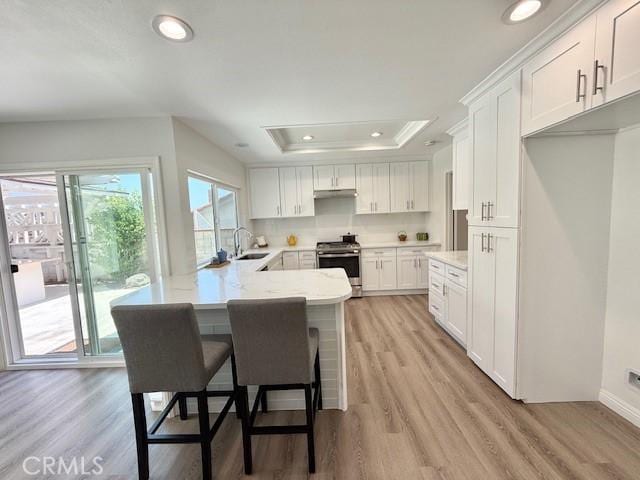 16413 Abascal Dr, Hacienda Heights, CA 91745 - kitchen with stainless steel electric range, a tray ceiling, a peninsula, white cabinets, and a breakfast bar