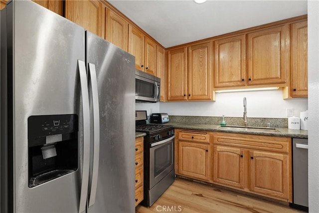 27074 Hidaway Ave Unit 3, Canyon Country, CA 91351 - kitchen with stainless steel appliances, light wood-style floors, dark stone countertops, and brown cabinets