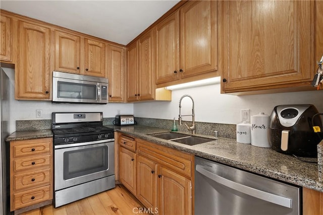 27074 Hidaway Ave Unit 3, Canyon Country, CA 91351 - kitchen featuring stainless steel appliances, light wood-type flooring, dark stone countertops, and brown cabinets