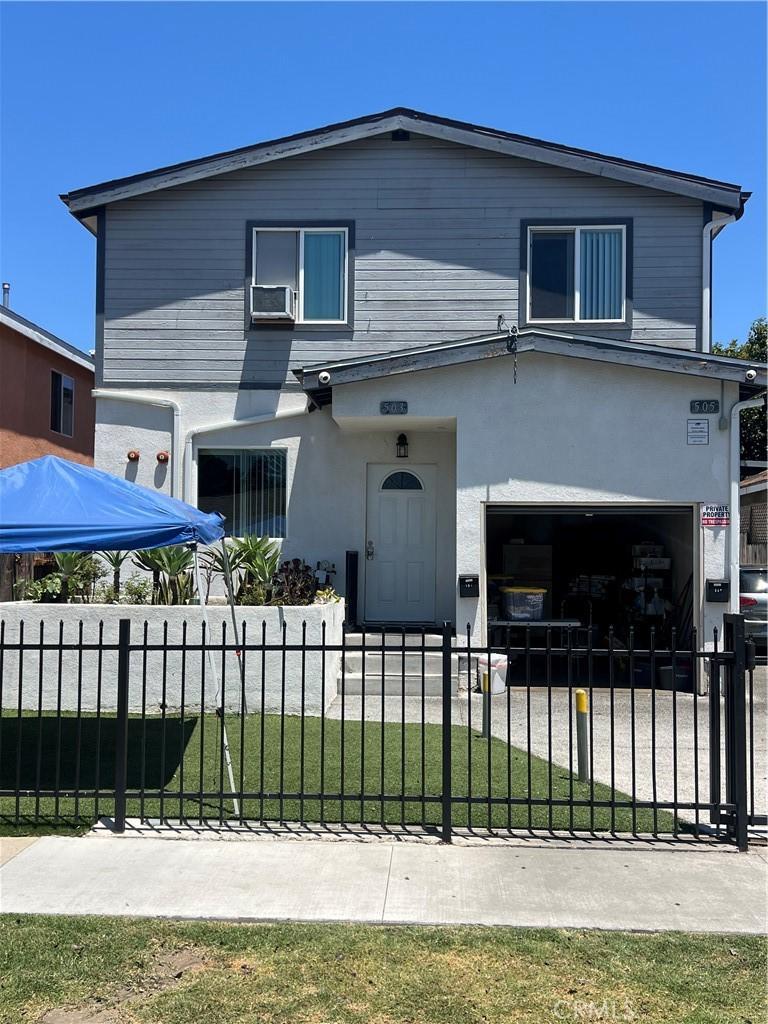 505 E 68th St, Los Angeles, CA 90003 - view of front facade with a garage, a fenced front yard, stucco siding, and cooling unit