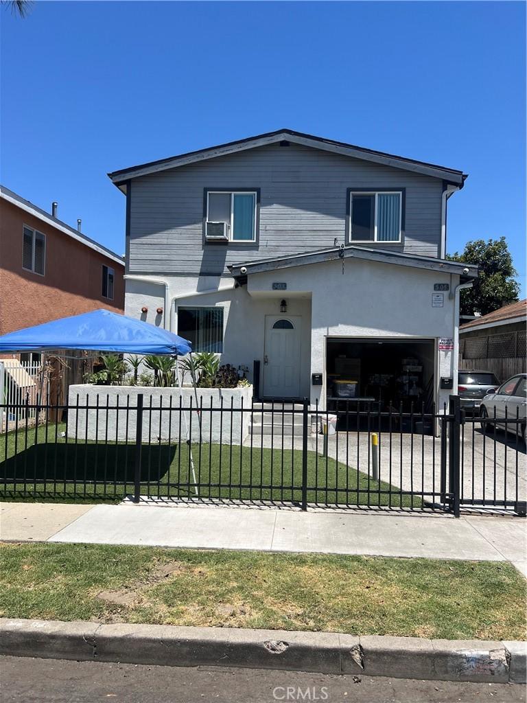 505 E 68th St, Los Angeles, CA 90003 - view of front of home with a garage, a fenced front yard, driveway, and stucco siding
