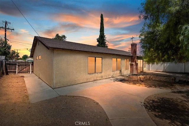 1897 Taylor Ave, Corona, CA 92882 - back of house at dusk with stucco siding, a fenced backyard, a patio, and a chimney