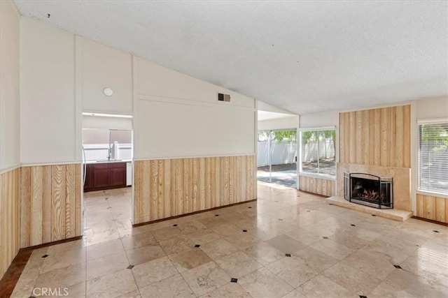 1897 Taylor Ave, Corona, CA 92882 - unfurnished living room featuring wood walls, wainscoting, a large fireplace, lofted ceiling, and a textured ceiling