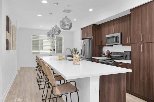 9958 Artesia Blvd Unit 1003, Bellflower, CA 90706 - kitchen featuring stainless steel appliances, a kitchen bar, a kitchen island with sink, light countertops, and recessed lighting