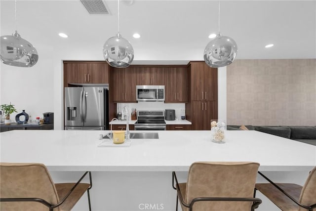 9958 Artesia Blvd Unit 1003, Bellflower, CA 90706 - kitchen with appliances with stainless steel finishes, light countertops, decorative light fixtures, a kitchen bar, and an island with sink
