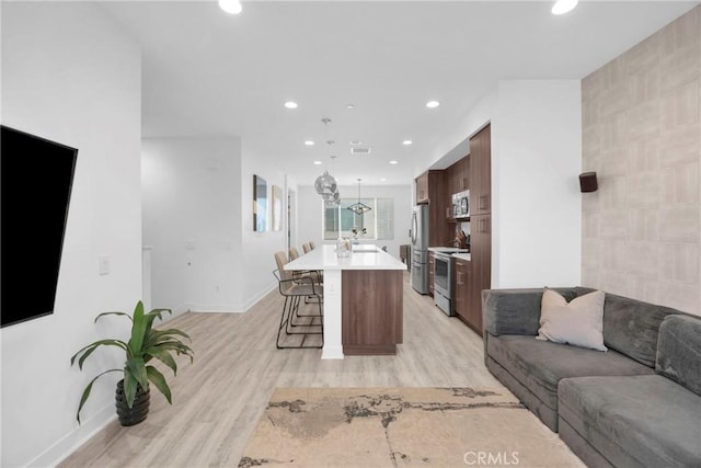 9958 Artesia Blvd Unit 1003, Bellflower, CA 90706 - kitchen featuring open floor plan, stainless steel appliances, a kitchen breakfast bar, light countertops, and light wood finished floors