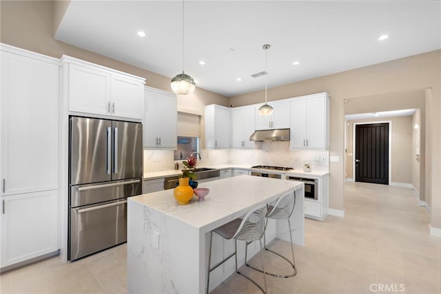 103 Winnett, Irvine, CA 92602 - kitchen with stainless steel appliances, under cabinet range hood, tasteful backsplash, a center island, and white cabinetry