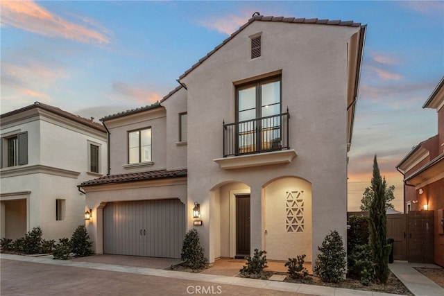 103 Winnett, Irvine, CA 92602 - mediterranean / spanish house featuring a tiled roof, a balcony, an attached garage, stucco siding, and a gate