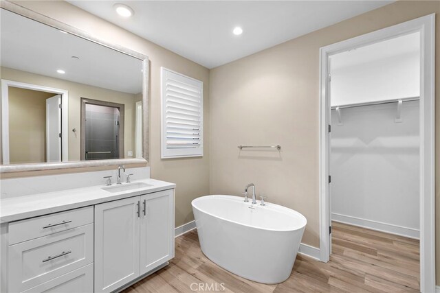 103 Winnett, Irvine, CA 92602 - bathroom with wood finished floors, vanity, a spacious closet, a soaking tub, and recessed lighting