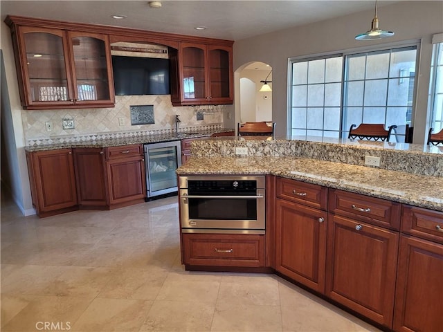 10840 New Salem Pt, San Diego, CA 92126 - kitchen featuring beverage cooler, oven, arched walkways, decorative backsplash, and light stone counters