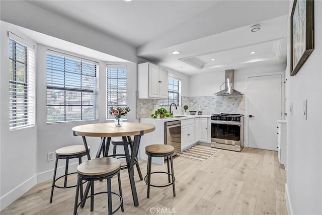 2633 Monte Carlo Dr Unit 41, Santa Ana, CA 92706 - kitchen with stainless steel appliances, wall chimney exhaust hood, tasteful backsplash, light wood-type flooring, and light countertops