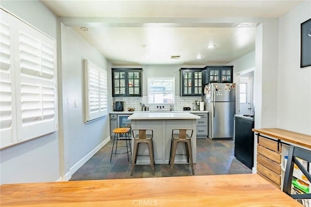 5855 Daneland St, Lakewood, CA 90713 - kitchen with freestanding refrigerator, a kitchen island, light countertops, glass insert cabinets, and a breakfast bar