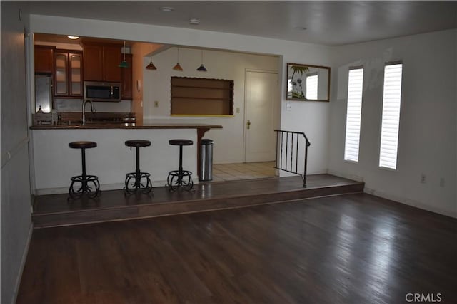 1331 Bothwell Ave, Colton, CA 92324 - kitchen with stainless steel microwave, dark countertops, wood finished floors, a peninsula, and a kitchen bar