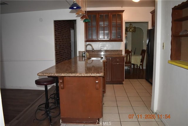 1331 Bothwell Ave, Colton, CA 92324 - kitchen featuring a kitchen bar, glass insert cabinets, light tile patterned floors, dark stone countertops, and open shelves