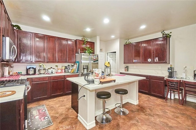 12672 Bellflower Ln, Moreno Valley, CA 92555 - kitchen featuring stainless steel appliances, light countertops, a center island with sink, a kitchen bar, and dark brown cabinets