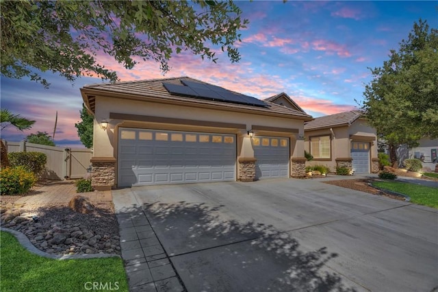 10844 Aster Ln, Apple Valley, CA 92308 - view of front of property featuring stone siding, solar panels, driveway, stucco siding, and a gate