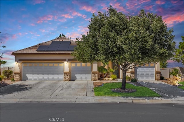10844 Aster Ln, Apple Valley, CA 92308 - view of front of house featuring solar panels, stucco siding, driveway, stone siding, and an attached garage