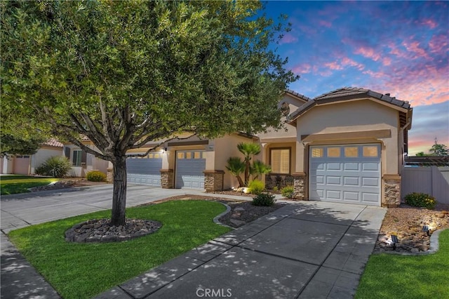 10844 Aster Ln, Apple Valley, CA 92308 - view of front of home featuring concrete driveway, stone siding, a garage, and stucco siding