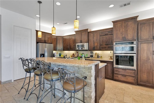 10844 Aster Ln, Apple Valley, CA 92308 - kitchen with appliances with stainless steel finishes, stone tile flooring, decorative backsplash, a breakfast bar, and recessed lighting