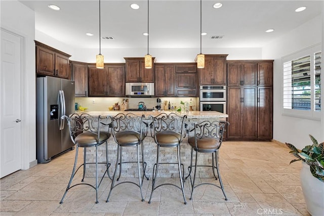 10844 Aster Ln, Apple Valley, CA 92308 - kitchen with appliances with stainless steel finishes, a kitchen breakfast bar, stone tile flooring, dark brown cabinets, and recessed lighting