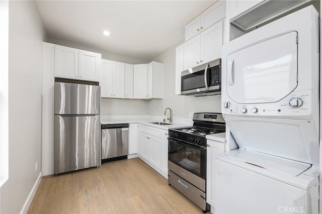1221 E 1st St, Long Beach, CA 90802 - kitchen with appliances with stainless steel finishes, stacked washing machine and dryer, light wood-type flooring, white cabinetry, and recessed lighting