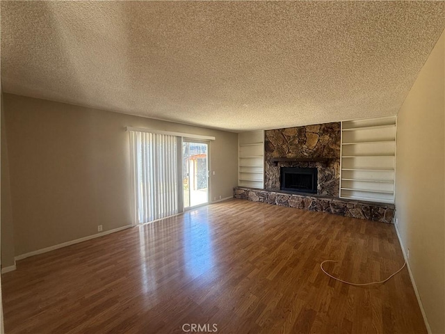 2854 Coronado Ave, San Diego, CA 92154 - unfurnished living room with wood finished floors, a textured ceiling, a stone fireplace, and built in shelves