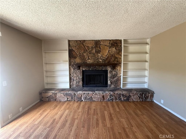 2854 Coronado Ave, San Diego, CA 92154 - unfurnished living room with built in features, wood finished floors, a textured ceiling, and a stone fireplace